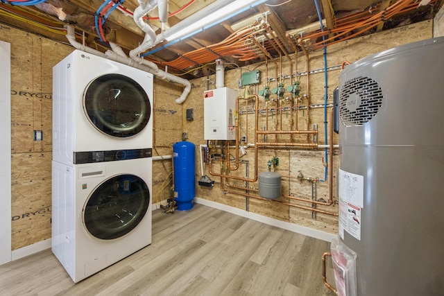 laundry area with electric water heater, light hardwood / wood-style flooring, water heater, and stacked washer / dryer