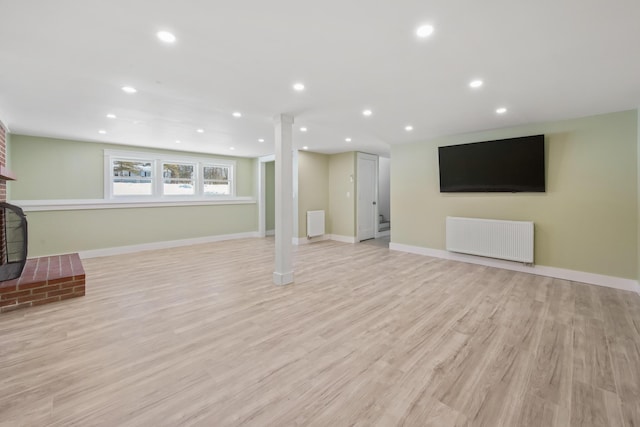 interior space featuring radiator, a fireplace, and light wood-type flooring