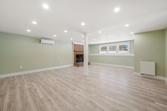 unfurnished living room with light hardwood / wood-style flooring, radiator, a brick fireplace, and an AC wall unit