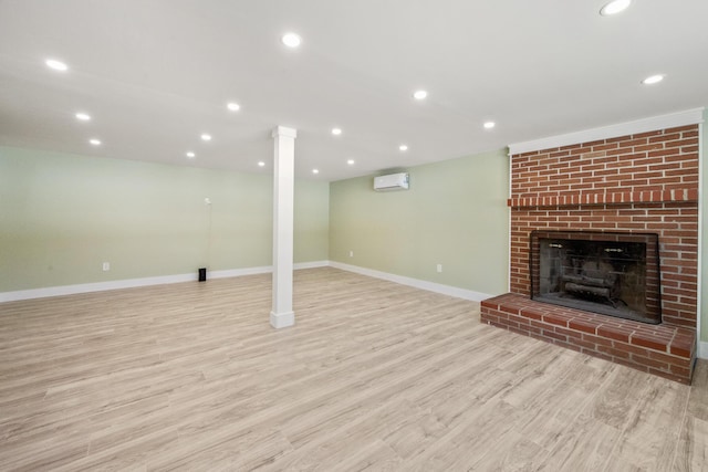 unfurnished living room featuring a brick fireplace, a wall mounted air conditioner, and light hardwood / wood-style flooring