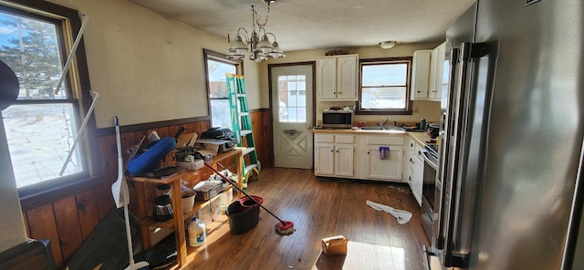 kitchen with high quality fridge, dark hardwood / wood-style floors, white cabinetry, sink, and hanging light fixtures