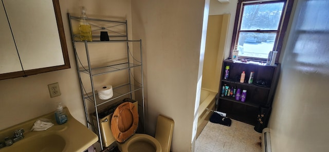 bathroom with sink, a bath, baseboard heating, and toilet