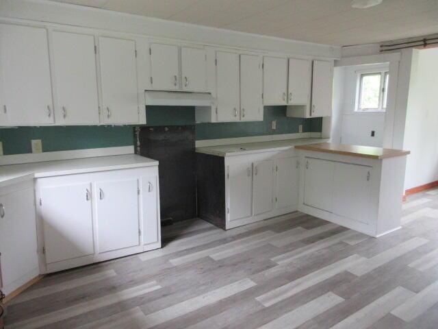 236 Frenchs Mill Rd, Sangerville, ME 04479 - kitchen with light wood-style floors, under cabinet range hood, white cabinetry, and light countertops