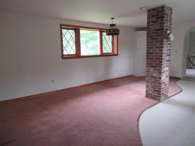 236 Frenchs Mill Rd, Sangerville, ME 04479 - unfurnished living room with carpet floors, baseboards, ornate columns, and arched walkways