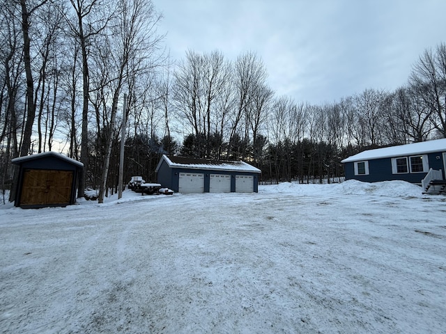 yard covered in snow featuring an outbuilding and a garage