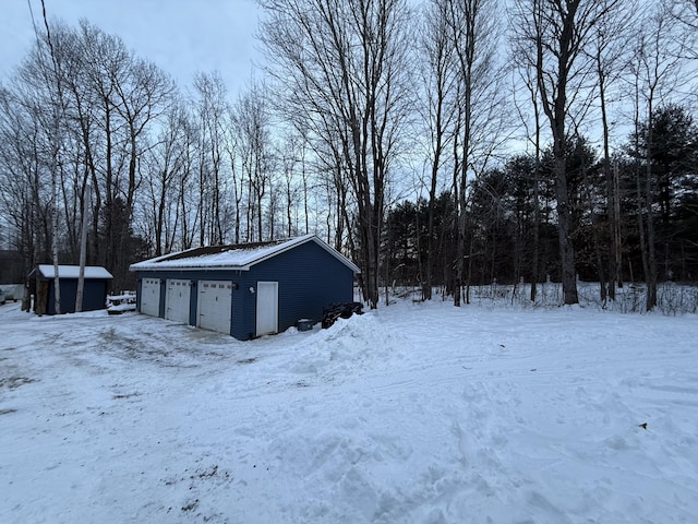 yard covered in snow with a garage and an outdoor structure