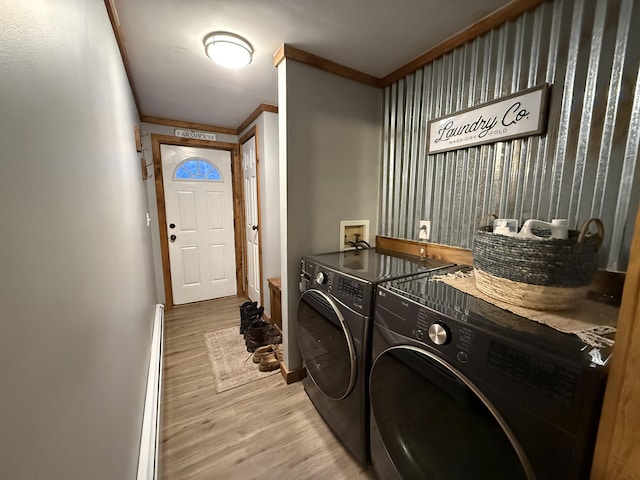 laundry room with hardwood / wood-style flooring, washing machine and clothes dryer, ornamental molding, and a baseboard radiator