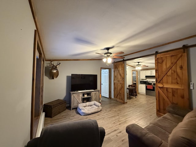 living room featuring ornamental molding, a barn door, ceiling fan, and light wood-type flooring