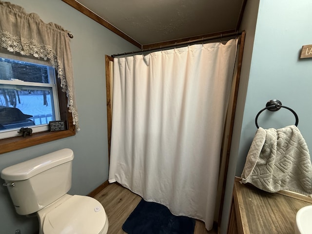 bathroom featuring hardwood / wood-style flooring, ornamental molding, walk in shower, and toilet