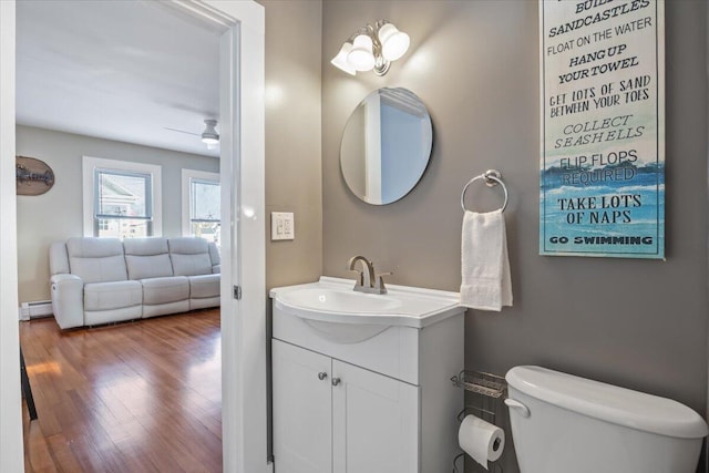 bathroom with ceiling fan, hardwood / wood-style floors, vanity, a baseboard radiator, and toilet