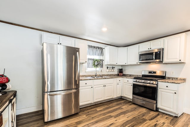 kitchen featuring a sink, dark wood finished floors, white cabinetry, appliances with stainless steel finishes, and baseboards