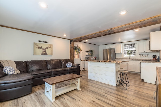 living area with beam ceiling, crown molding, recessed lighting, and light wood-style floors