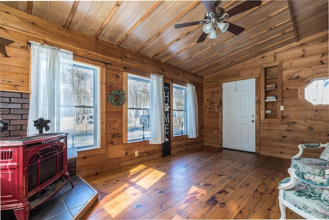 foyer with hardwood / wood-style floors, wooden ceiling, a wood stove, and wood walls