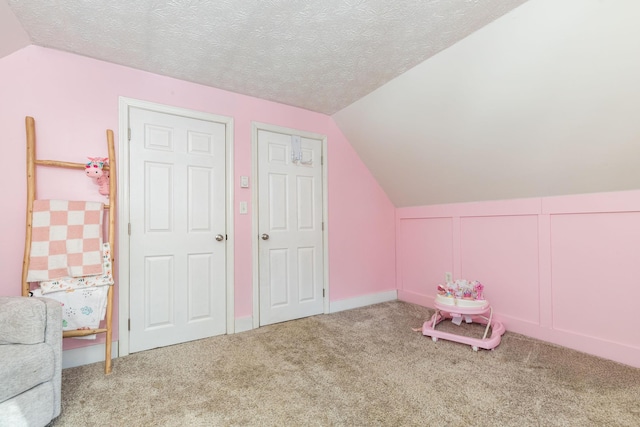 game room with a textured ceiling, carpet flooring, and vaulted ceiling