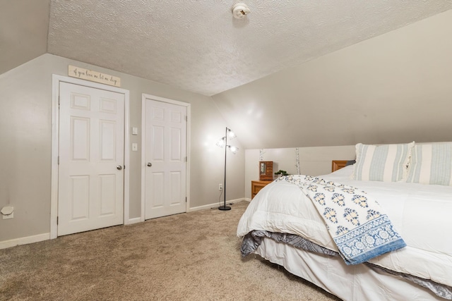 carpeted bedroom with vaulted ceiling, baseboards, and a textured ceiling