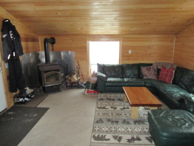 living room with wooden walls, vaulted ceiling, a wood stove, and wooden ceiling