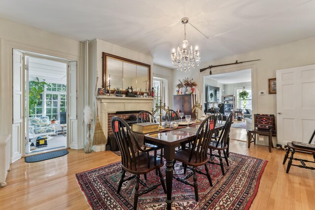 823 Washington St, Bath, ME 04530 - dining room featuring plenty of natural light, a chandelier, a fireplace, and light hardwood / wood-style flooring