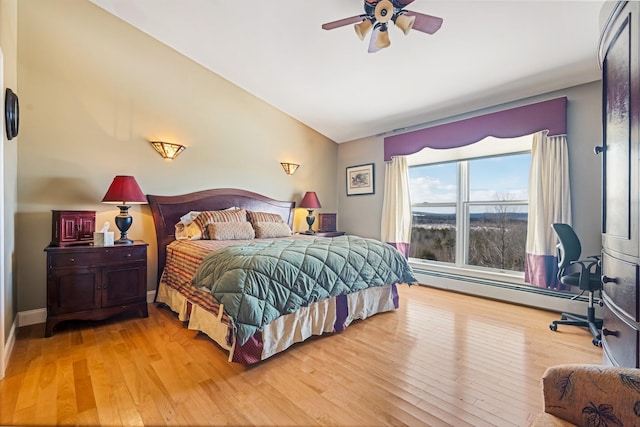 bedroom with vaulted ceiling, hardwood / wood-style floors, baseboard heating, and baseboards