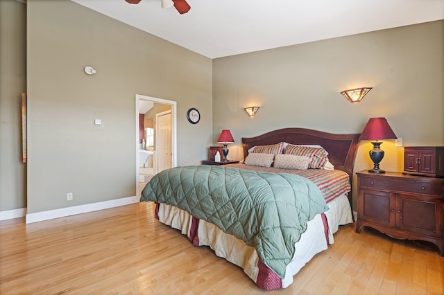 bedroom with baseboards, light wood finished floors, and ensuite bathroom