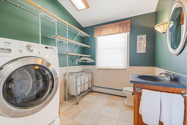 laundry room featuring laundry area, a sink, baseboard heating, wainscoting, and washer / clothes dryer