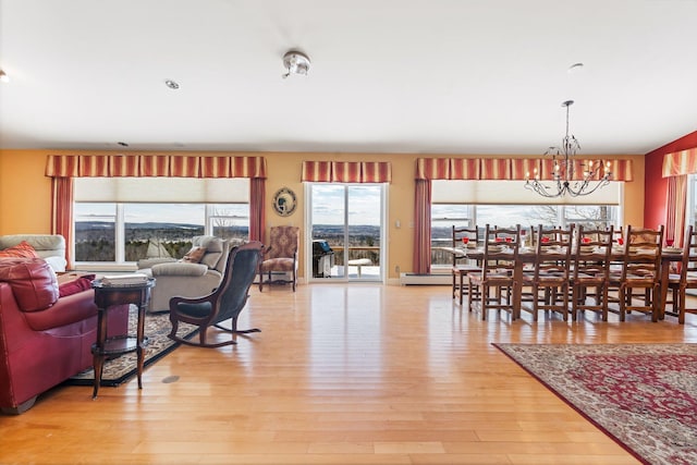 living area with light wood-style floors, a baseboard heating unit, and a notable chandelier