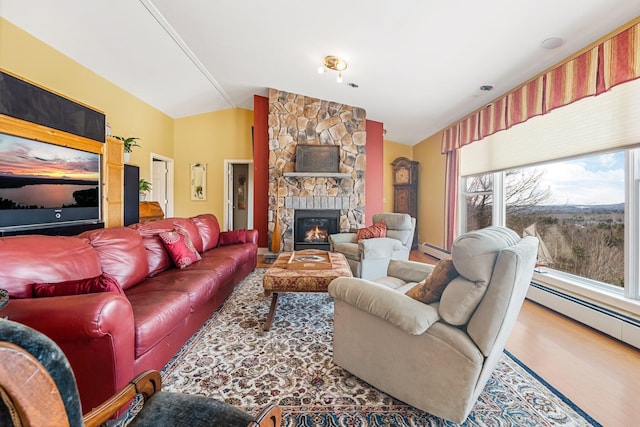 living room with lofted ceiling, a baseboard heating unit, wood finished floors, and a stone fireplace