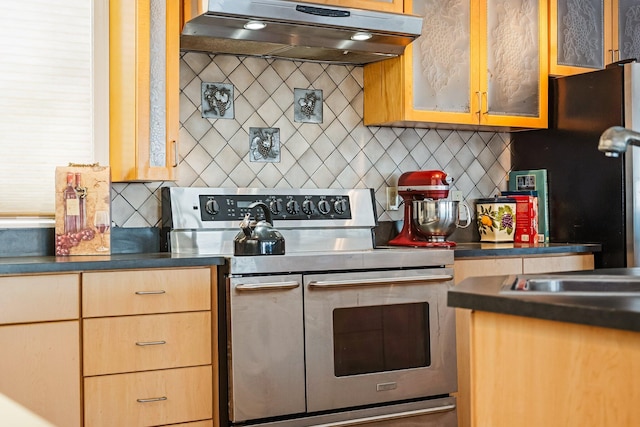 kitchen with glass insert cabinets, freestanding refrigerator, under cabinet range hood, double oven range, and backsplash