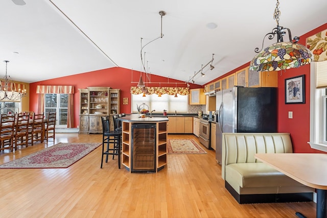 kitchen with light wood finished floors, open shelves, stainless steel appliances, dark countertops, and a sink