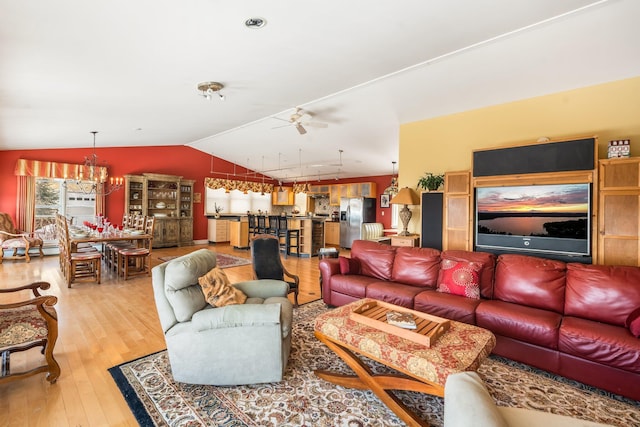 living room featuring light wood finished floors, vaulted ceiling, and ceiling fan with notable chandelier