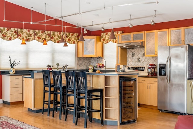 kitchen featuring light wood-style flooring, under cabinet range hood, beverage cooler, stainless steel fridge with ice dispenser, and dark countertops