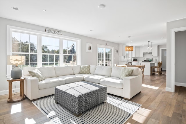 living area with light wood-style flooring, baseboards, and recessed lighting