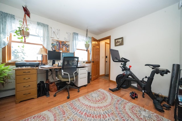 home office with a baseboard radiator, plenty of natural light, and light hardwood / wood-style flooring