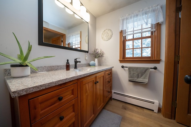 bathroom with hardwood / wood-style flooring, a baseboard radiator, and vanity