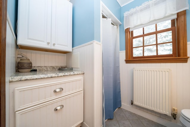 bathroom featuring radiator heating unit, tile patterned floors, and toilet