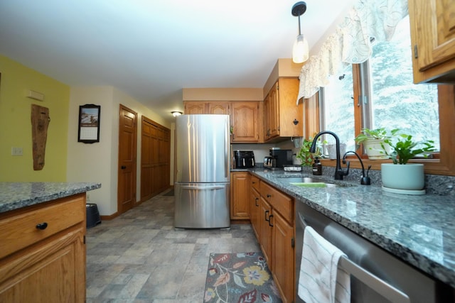 kitchen featuring stainless steel appliances, sink, pendant lighting, and stone counters