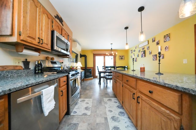 kitchen with stainless steel appliances, pendant lighting, an inviting chandelier, and dark stone counters