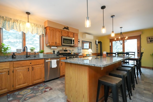 kitchen with a kitchen bar, light stone counters, a wall unit AC, a kitchen island, and stainless steel appliances