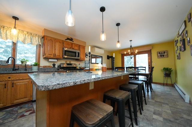 kitchen with sink, a breakfast bar area, baseboard heating, stainless steel appliances, and a center island