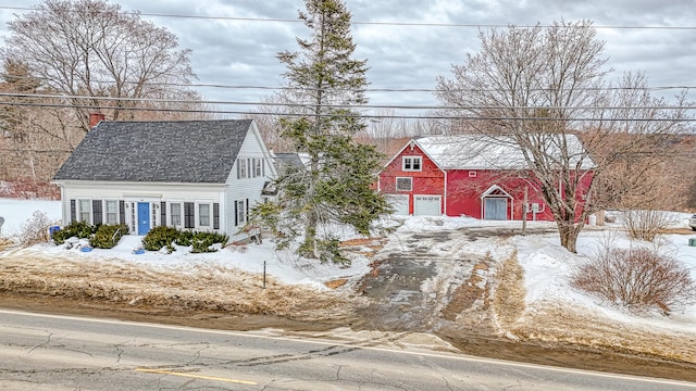 cape cod home with a barn and a shingled roof