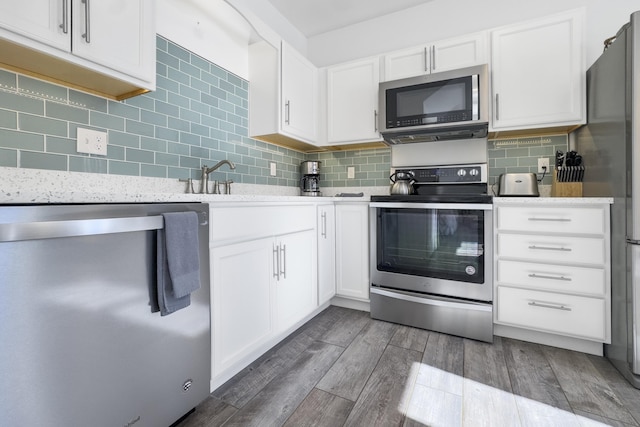 kitchen with dark wood-type flooring, sink, appliances with stainless steel finishes, white cabinets, and backsplash
