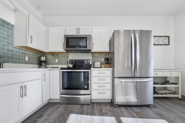 kitchen featuring dark wood-type flooring, appliances with stainless steel finishes, backsplash, light stone countertops, and white cabinets