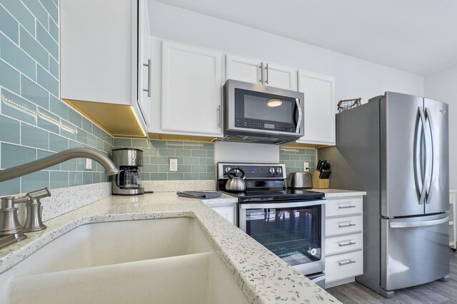 kitchen with sink, white cabinetry, light stone counters, tasteful backsplash, and stainless steel appliances