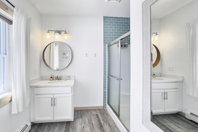 bathroom featuring a shower with door, vanity, and baseboard heating