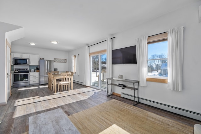 interior space with dark hardwood / wood-style floors, a wealth of natural light, and a baseboard heating unit