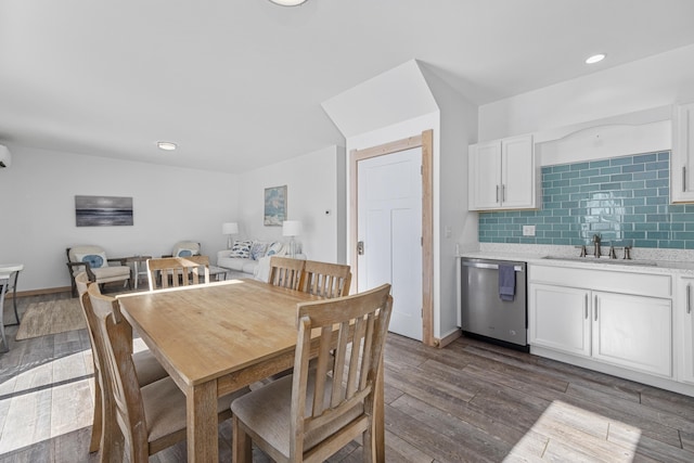 dining area with dark wood-type flooring, a wall mounted AC, and sink