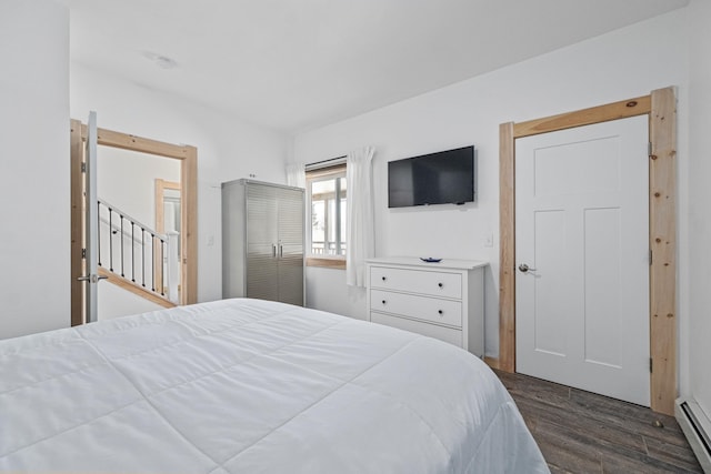 bedroom with baseboard heating and dark hardwood / wood-style flooring