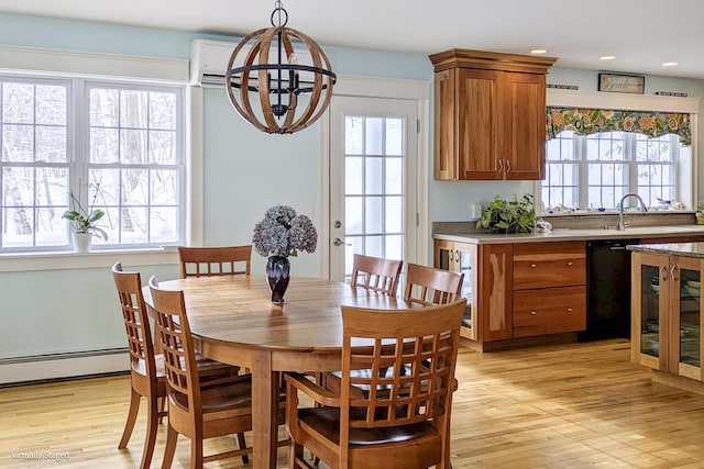 dining area with a baseboard radiator, plenty of natural light, and light wood-type flooring