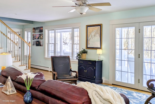 living room with light hardwood / wood-style flooring, a baseboard radiator, and ceiling fan