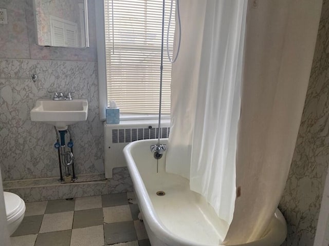 bathroom with a tub, a healthy amount of sunlight, radiator heating unit, and toilet