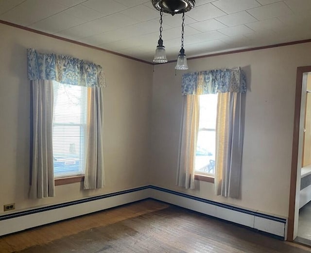 empty room featuring hardwood / wood-style floors, crown molding, and baseboard heating